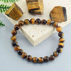 Tiger eye beaded bracelet on a light stone surface with tiger eye stones.