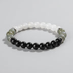 Beaded bracelet with black, white, and green stones on a wooden surface with 'Self-Love' text.