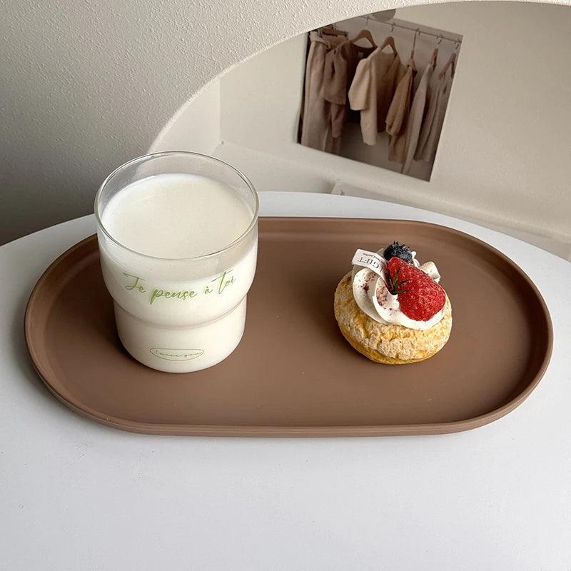 Candle and dessert on a brown tray with a mirror reflecting clothing in the background