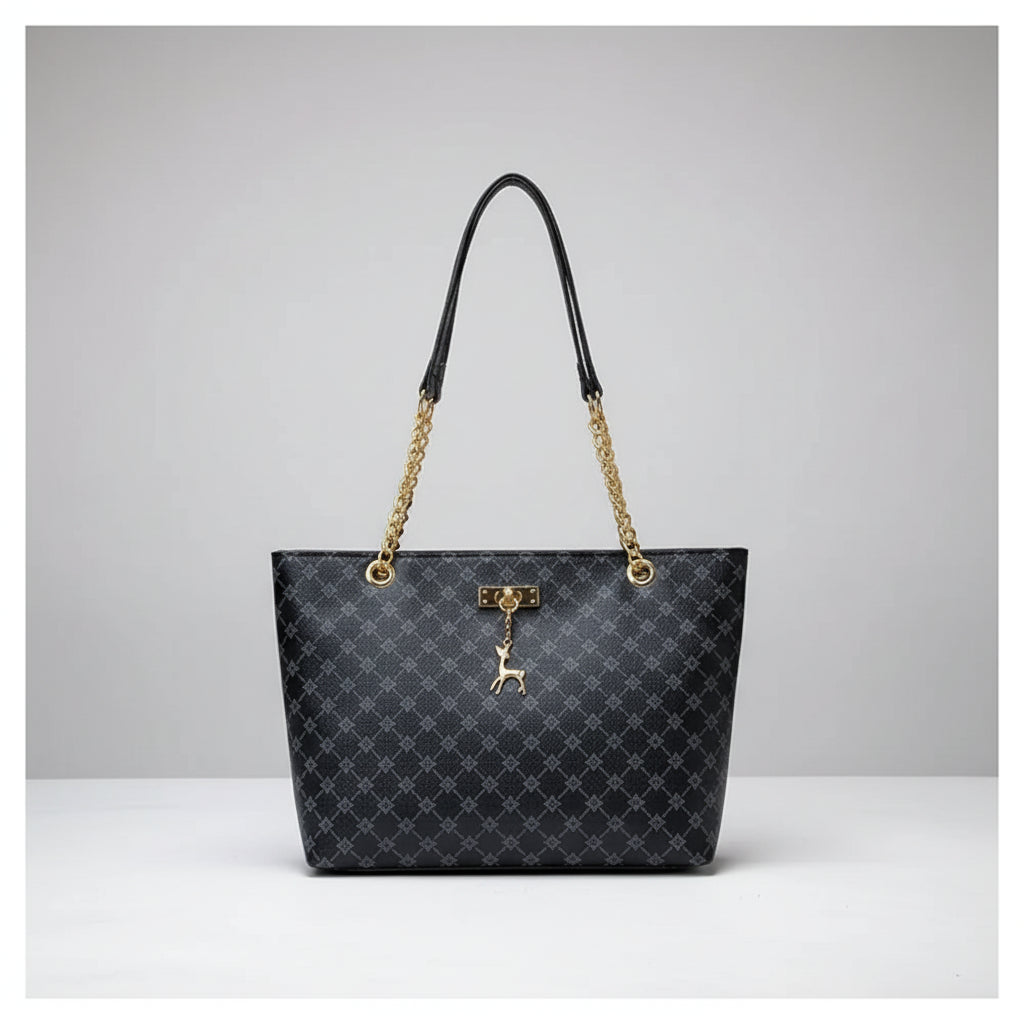 Black patterned handbag with gold chain and handle against a white wall.