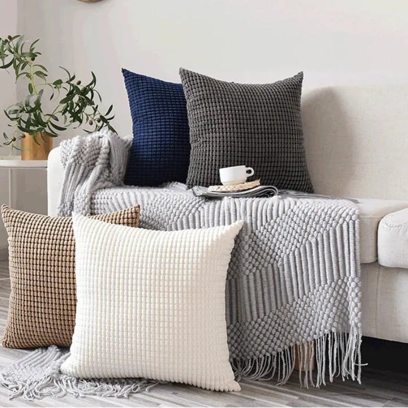 Decorative pillows and a blanket on a sofa in a living room setting.