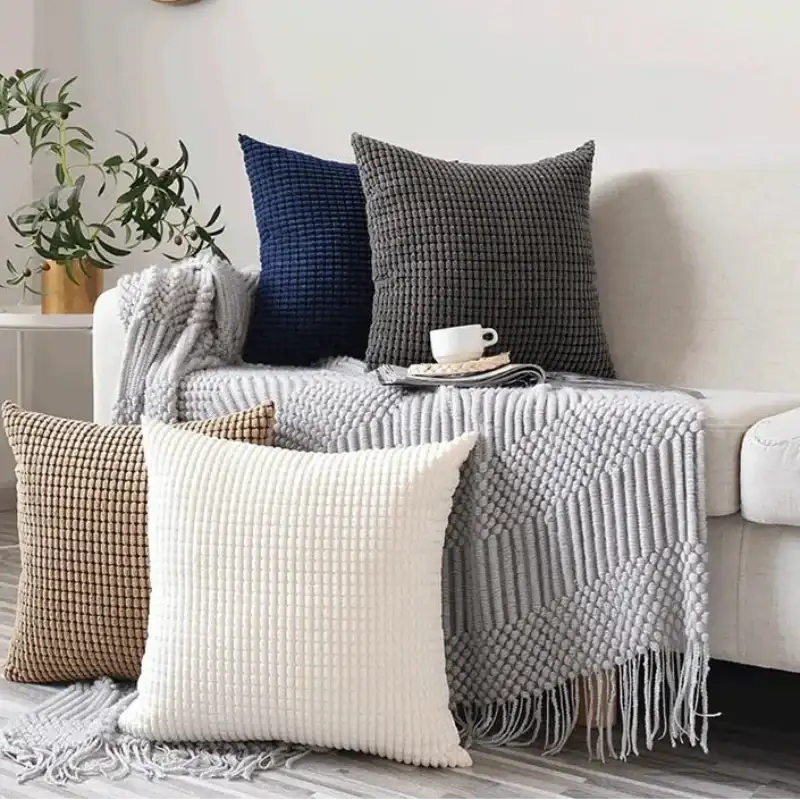 Decorative pillows and a blanket on a sofa in a living room setting.