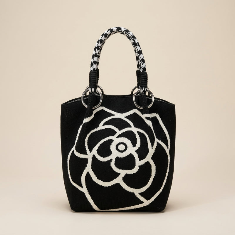 Woman holding a black handbag with white floral pattern on a city street