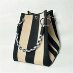 Black and beige striped handbag with a braided handle on a light gray background