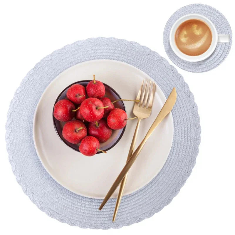 Placemat with bowl of red apples, gold fork, knife, and cup of coffee on a white background