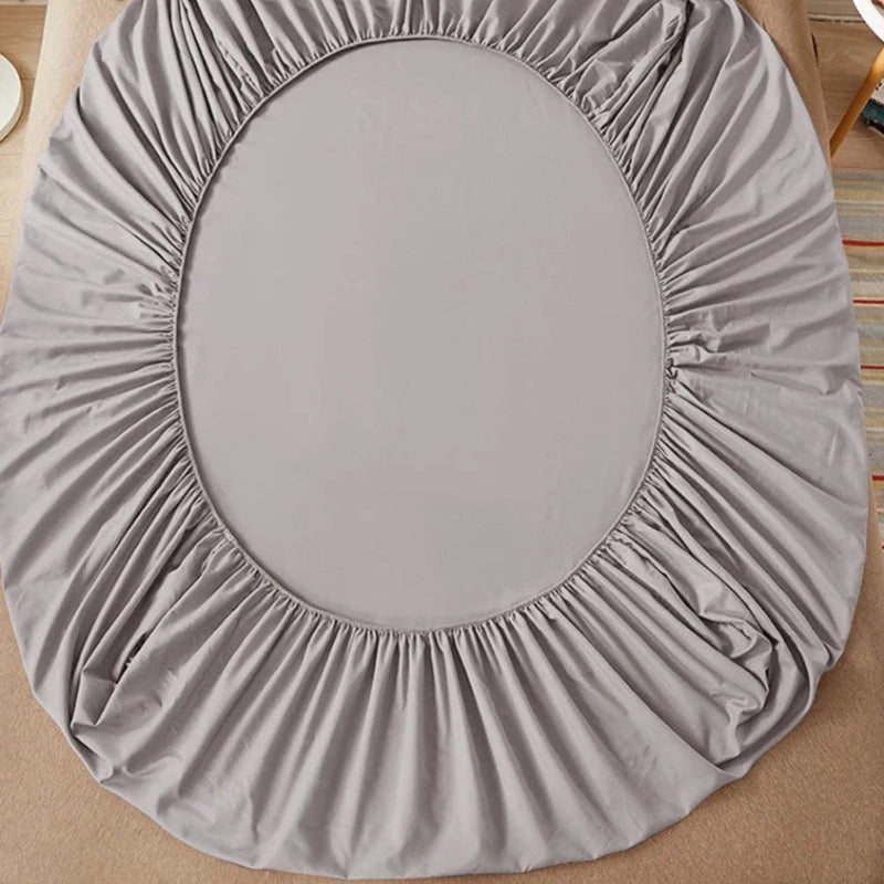 Gray fitted sheet on a bed with 'vave' branding.