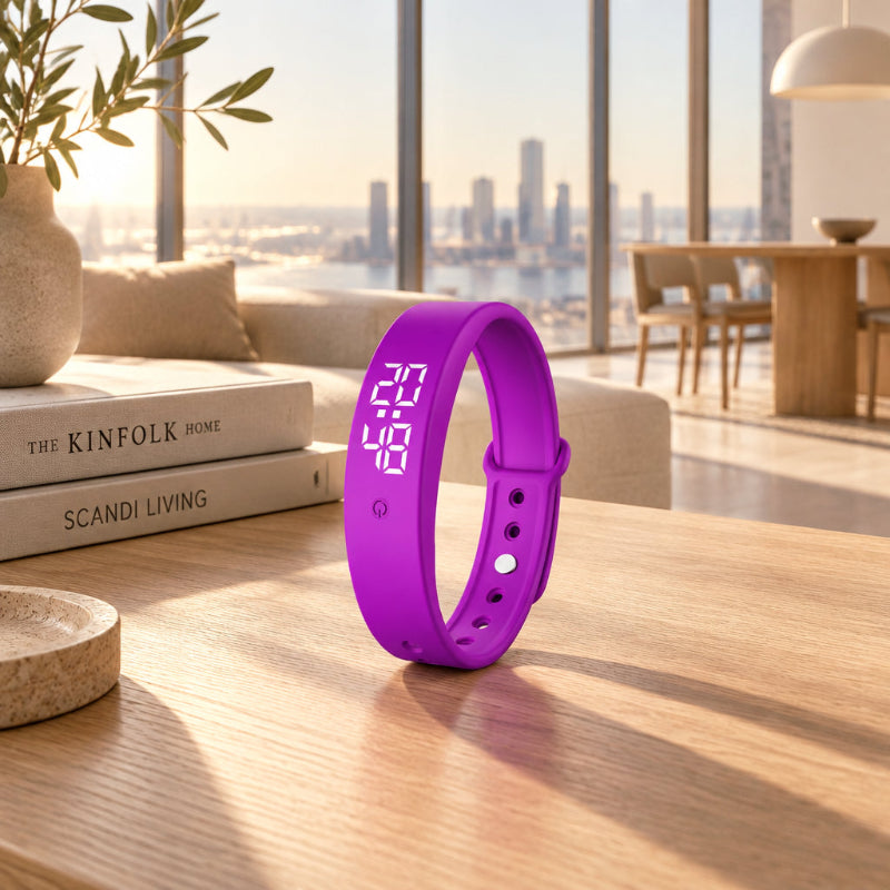 A purple silicone smart wristband with a digital LED display showing '6:23' and '100' stands on a wooden table in a modern, sunlit living room setting.