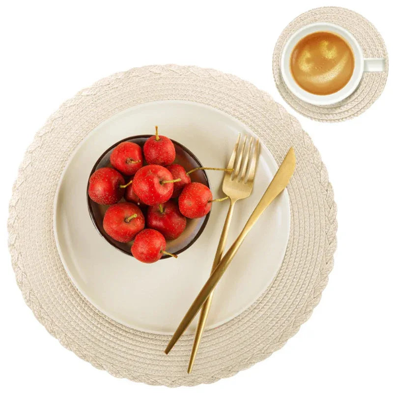 Dinner setting with a bowl of red apples, gold fork and knife, and a cup of coffee on a white background.