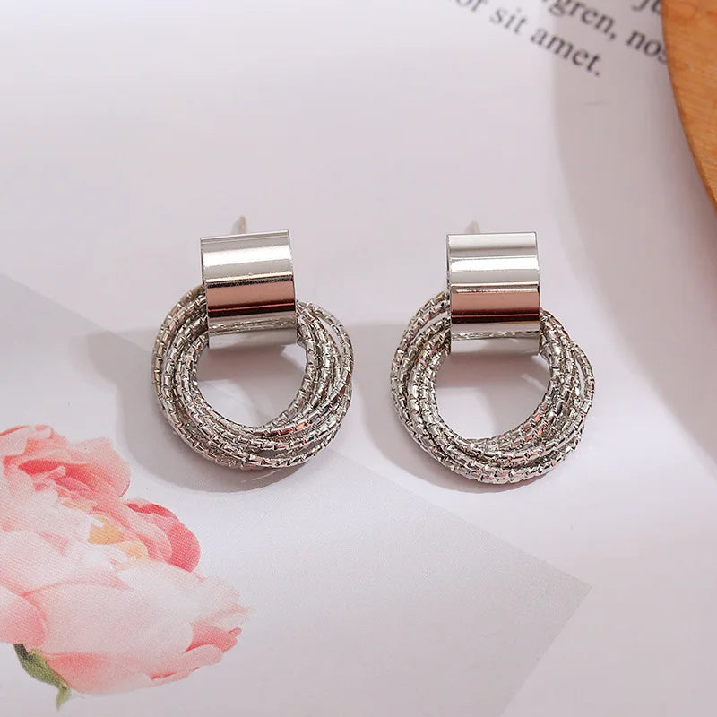 Silver circular earrings on a light background with floral elements
