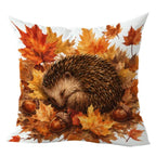Square throw pillow featuring a printed design of a sleeping hedgehog nestled among orange and yellow autumn leaves and acorns, shown on a white background.