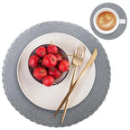 Gray woven placemat with a bowl of cherries, gold fork and knife, and a cup of coffee.