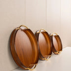 Set of three wooden trays with gold handles on a neutral background