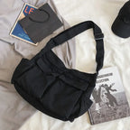 Black shoulder bag on a light-colored surface with books and a cap.
