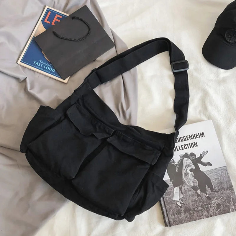 Black shoulder bag on a light-colored surface with books and a cap.
