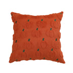 An orange textured throw pillow featuring a raised pumpkin pattern with small green stems, shown against a plain white background.