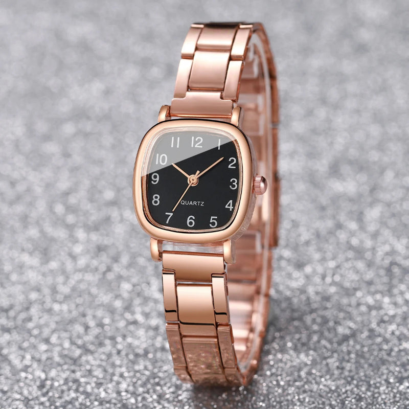 Rose gold watch with a black face on a gray glittery background