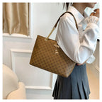 Person holding a brown patterned handbag with a gold chain strap indoors.
