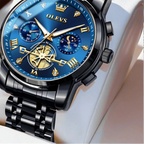 Luxury watch with blue face and black metal strap on a white cushion, brand 'OLEVS' visible.