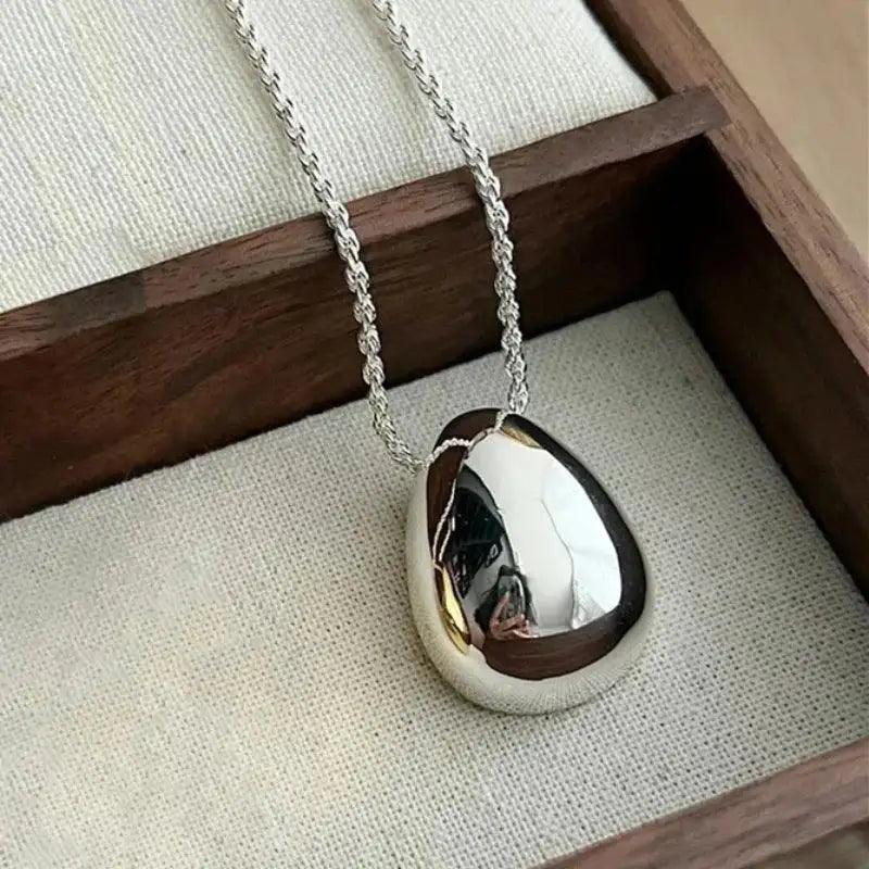 Silver necklace with a unique pendant on a wooden surface