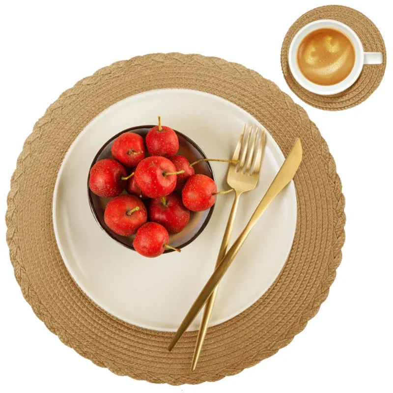 Table setting with a bowl of red apples, gold cutlery, and a cup of coffee on a woven placemat.