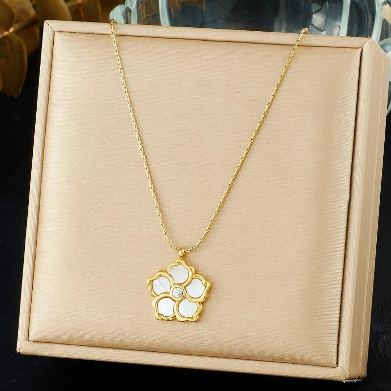 Gold necklace with a floral pendant on a beige display box.