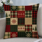 A square throw pillow with a patchwork Christmas pattern, featuring red, green, beige, and black plaid, snowflakes, pine trees, and herringbone designs, resting on a light gray sofa.