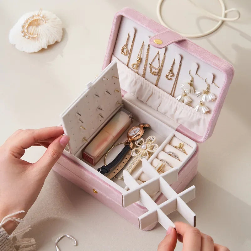 Pink jewelry box with gold jewelry inside, held by a person.