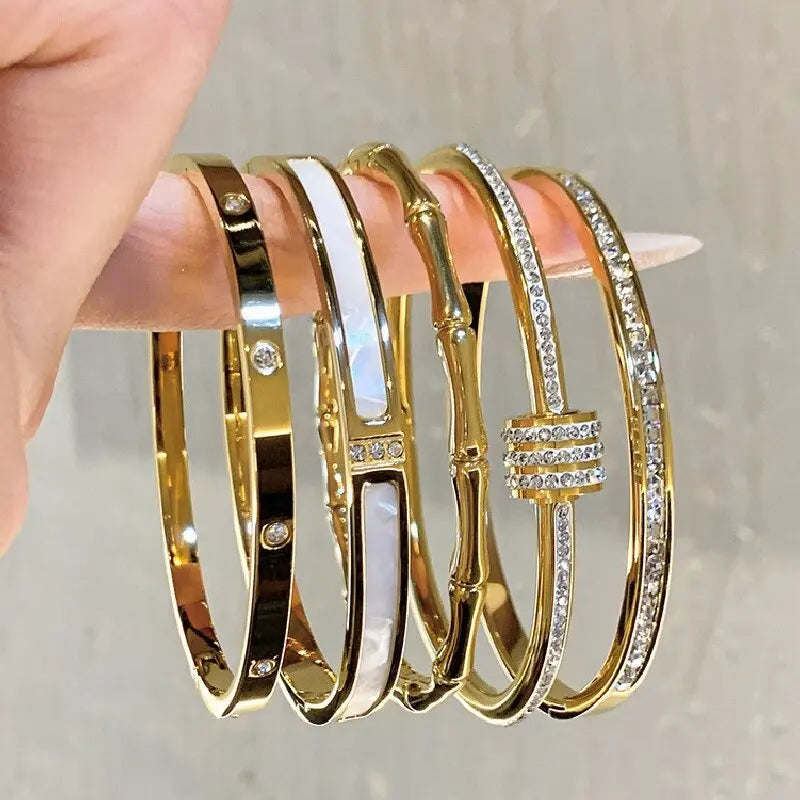 Set of gold bangles with diamond accents on a hand against a neutral background