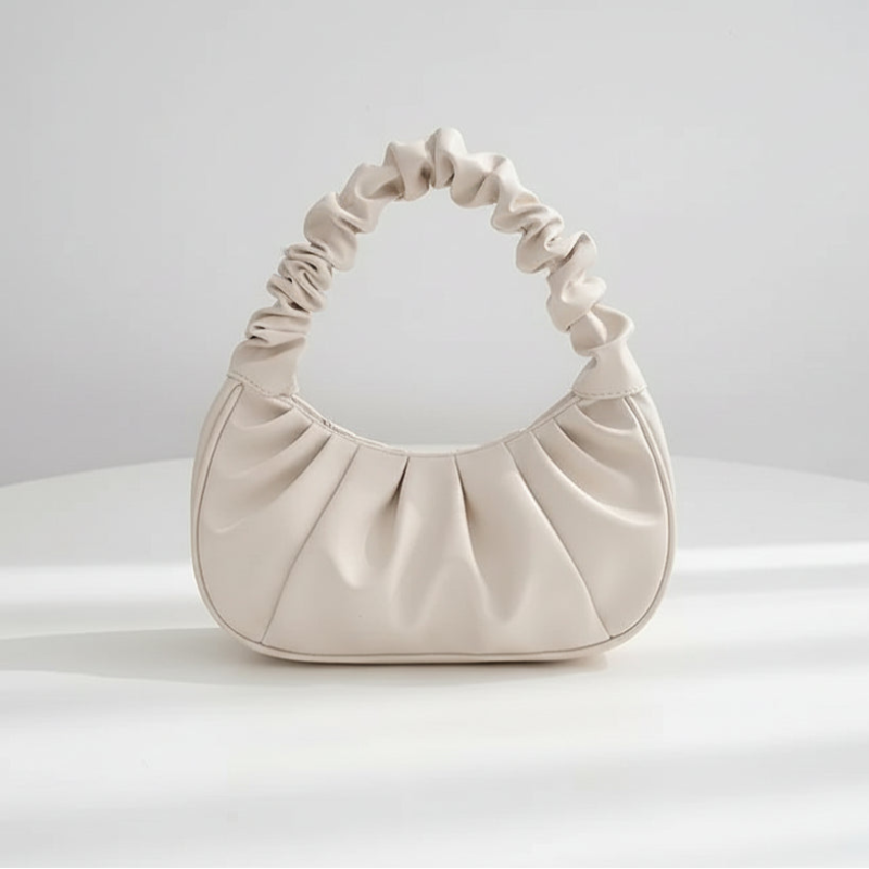 White handbag with black handle on a white surface