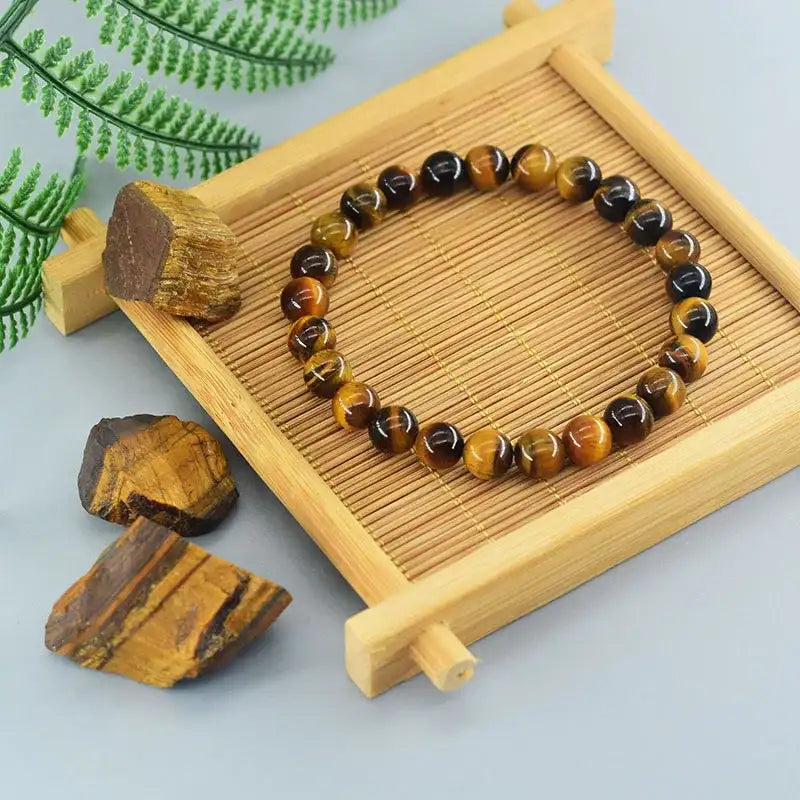 Tiger eye bracelet on a wooden tray with tiger eye stones and a plant in the background