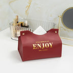 Red pouch with 'ENJOY' text on a white surface with decorative items in the background