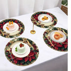 Three round Christmas-themed placemats with red poinsettias, green holly, gold bows, and white plates are arranged on a white tablecloth. Each placemat is styled with a white plate, gold cutlery, and a small dessert or pastry.