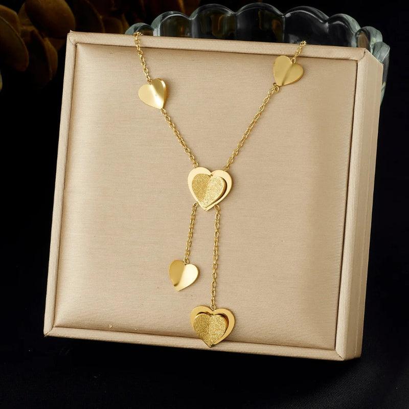 Gold heart-shaped necklace on a beige display box with a black background