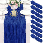 Blue table runner and yarn on a white table setting with flowers and cutlery.