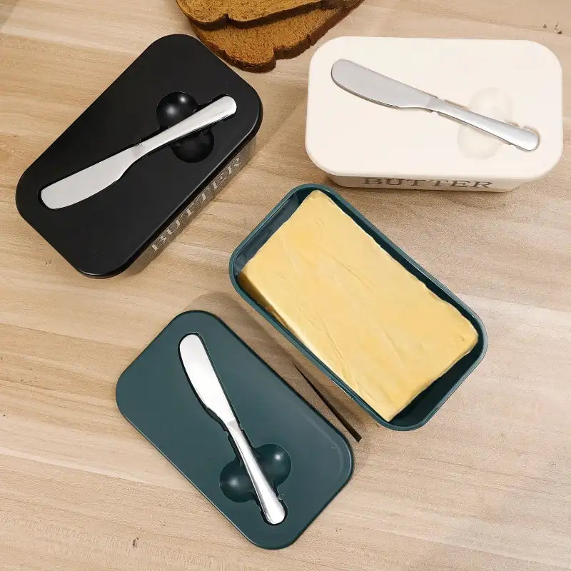 Butter containers with lids and butter knives on a wooden surface