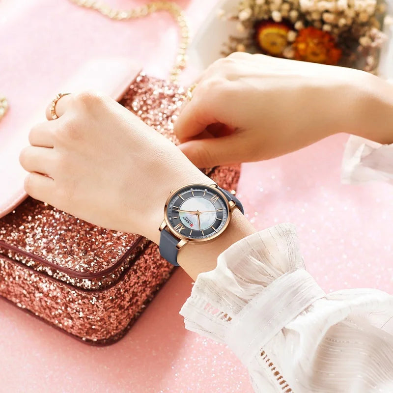 Person wearing a watch with a pink glittery bag and flowers in the background