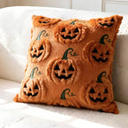 An orange plush throw pillow with a raised jack-o'-lantern pattern, resting on a white textured sofa.