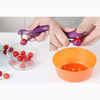 Purple cherry pitter being used to remove cherry pits from a bowl.