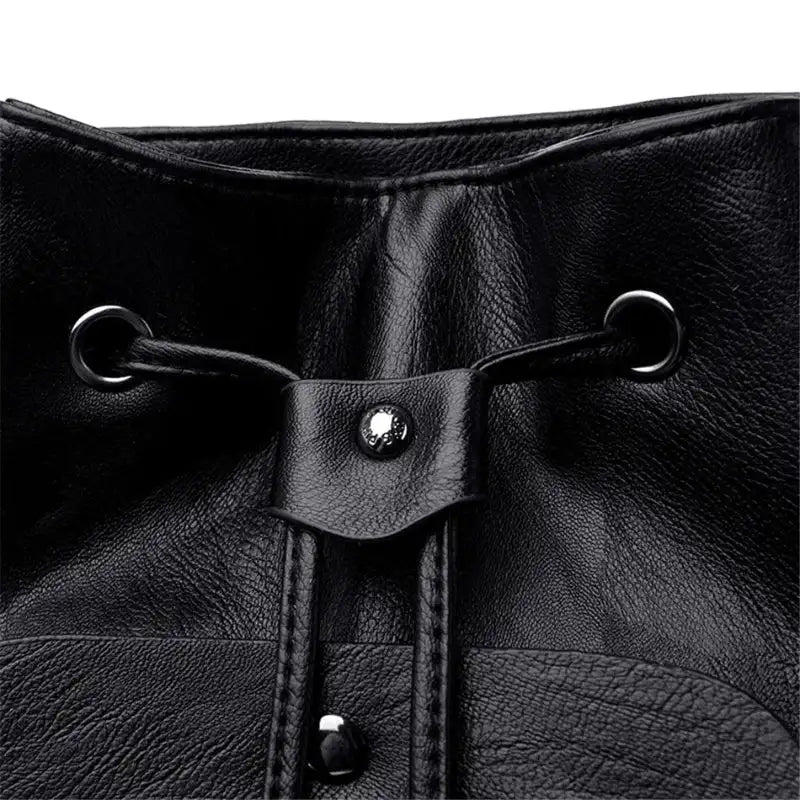 Close-up of a black leather drawstring bag with metal loops and buttons.
