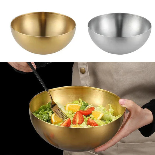Two metal bowls, one gold and one silver, with a person holding a gold bowl filled with salad.