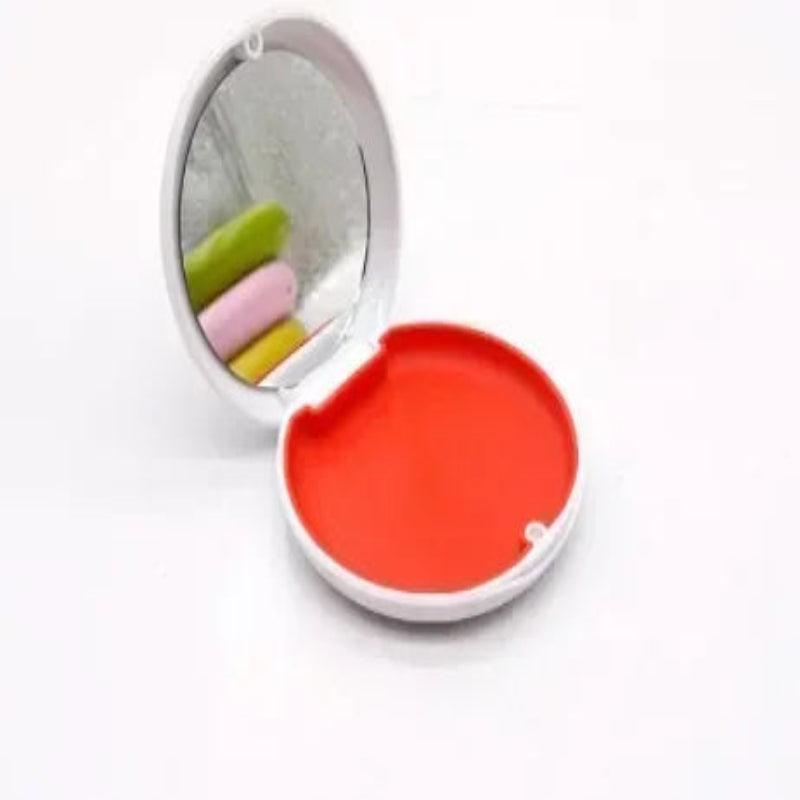 Compact mirror with colorful lip balm inside on a white background