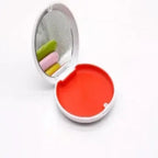 Compact mirror with colorful lip balm inside on a white background