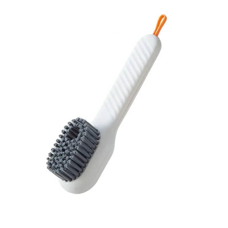 Cleaning brush with white handle, gray scrubber, and orange end on a white background