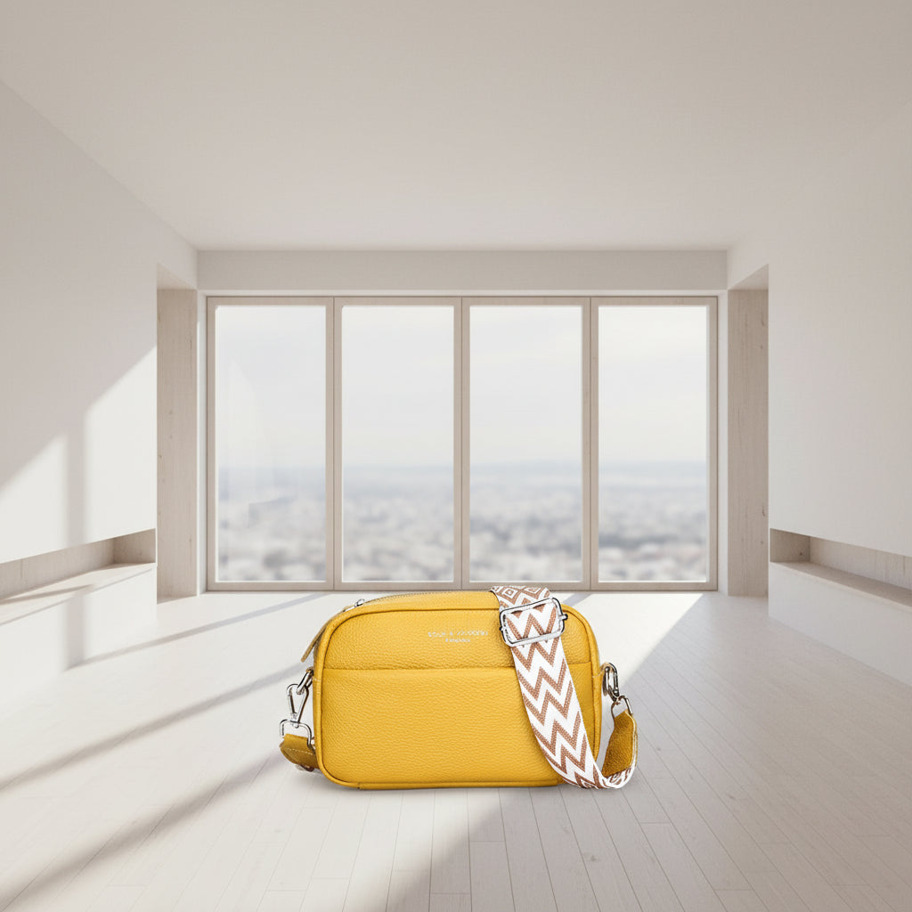 Yellow crossbody bag with a patterned strap on a white background