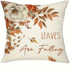 Square decorative throw pillow with a cream background, featuring a floral design in white, orange, and brown, with the text 'LEAVES Are Falling' printed on the front.