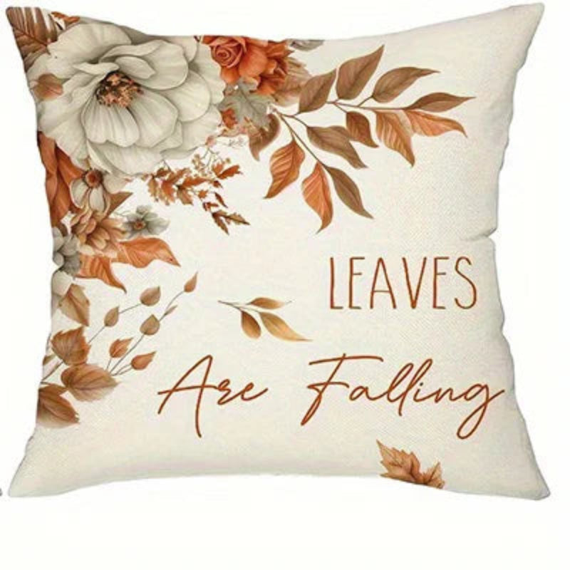 Square decorative throw pillow with a cream background, featuring a floral design in white, orange, and brown, with the text 'LEAVES Are Falling' printed on the front.