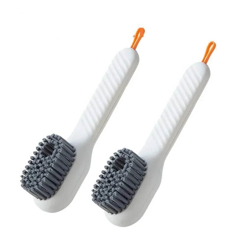 Two white cleaning brushes with gray bristles and orange handles on a white background.
