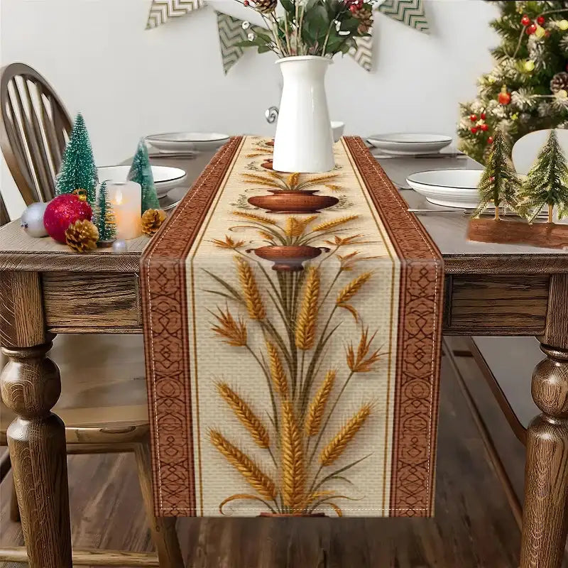 A woven table runner with a wheat and stalk pattern in gold, brown, and beige, styled on a wooden dining table with holiday decorations.
