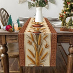 A woven table runner with a wheat and stalk pattern in gold, brown, and beige, styled on a wooden dining table with holiday decorations.