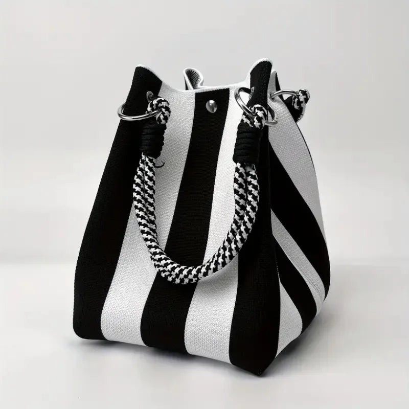 Black and white striped handbag with braided handles on a light gray background